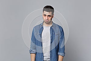 Handsome stylish unshaven young man in denim jeans shirt posing isolated on grey wall background studio portrait. People