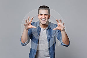 Handsome stylish unshaven young man in denim jeans shirt posing isolated on grey wall background studio portrait. People