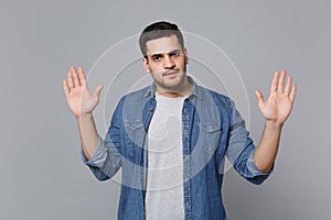 Handsome stylish unshaven young man in denim jeans shirt posing isolated on grey wall background studio portrait. People