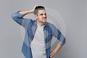 Handsome stylish unshaven young man in denim jeans shirt posing isolated on grey wall background studio portrait. People