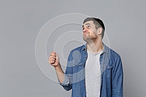 Handsome stylish unshaven young man in denim jeans shirt posing isolated on grey wall background studio portrait. People