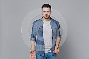 Handsome stylish unshaven young man in denim jeans shirt posing isolated on grey wall background studio portrait. People