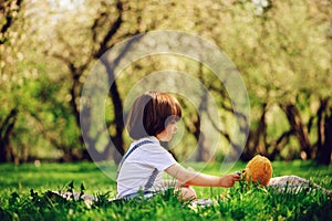 Handsome stylish 3 years old toddler child boy with funny face in suspenders enjoying sweets on picnic in spring