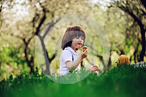 Handsome stylish 3 years old toddler child boy with funny face in suspenders enjoying sweets on picnic in spring