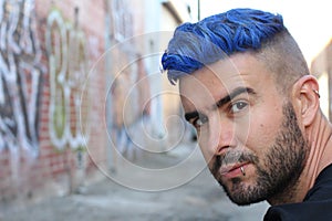 Handsome stylish young man with artificially coloured blue dyed hair undercut hairstyle, beard and piercings with copy space