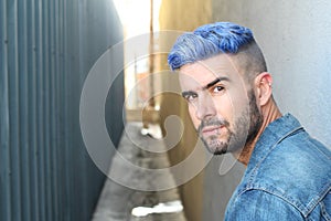 Handsome stylish young man with artificially coloured blue dyed hair undercut hairstyle, beard and piercings with copy space