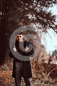 A handsome stylish young man posing in the autumn forest.