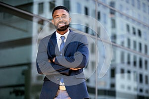 Handsome successful businessman standing with arms folded outside next to financial buildings, possible CEO, entrepreneur, corpora