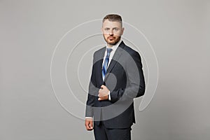 Handsome successful confident young business man in classic black suit shirt posing isolated on grey wall background