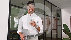 Handsome successful hispanic male entrepreneur using smartphone indoors