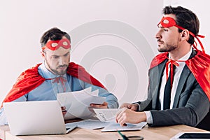 handsome super businessmen in masks and capes working with documents
