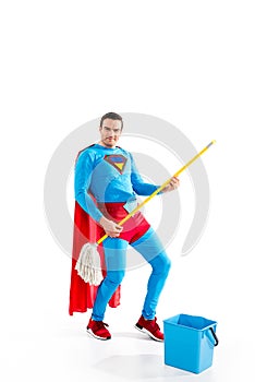 handsome superhero having fun with mop and smiling at camera