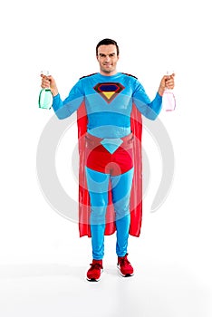 handsome superman holding spray bottles and smiling at camera