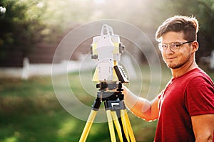 handsome surveyor working with total station with coordinates, cartography industry details photo