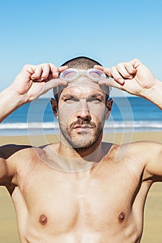 Handsome swimmer putting on goggles