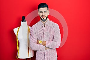 Handsome tailor man with beard with arms crossed gesture winking looking at the camera with sexy expression, cheerful and happy