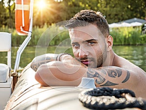 Handsome tattooed young man in boat