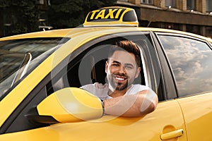 Handsome taxi driver in car on city street