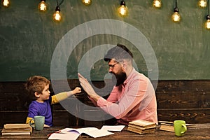 Handsome teacher and cute kid playing in classroom. Schoolboy achieving the task. Little champion salutation