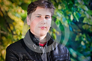 Handsome teen portrait in autumn leaves background