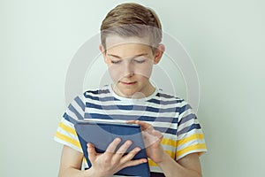 Handsome teen schoolboy standing with tablet and learning