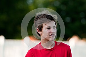 Handsome teenage boy outdoors with braces and messy hair.