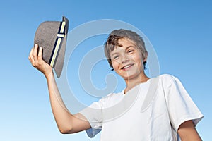 Handsome teenage boy standing outside against a blue sky