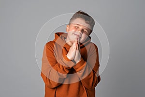 Handsome teenager boy appreciate help, thanking and bowing politely with namaste gesture, pray wish beg ask luck expect, gray