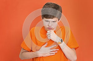 Handsome teenager boy coughing, suffering from illness such as a cold or the flu, feeling unwell and feverish
