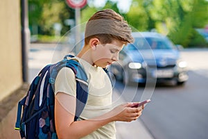 Handsome teenager boy playing the smartphone mobile games does not pay attention to the moving car. Preteen child