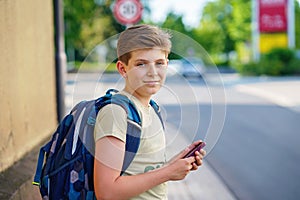 Handsome teenager boy playing the smartphone mobile games does not pay attention to the moving car. Preteen child