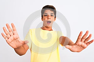 Handsome teenager boy standing over white isolated background afraid and terrified with fear expression stop gesture with hands,