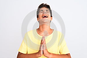 Handsome teenager boy standing over white isolated background begging and praying with hands together with hope expression on face