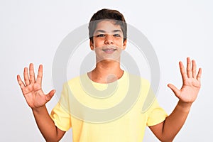 Handsome teenager boy standing over white isolated background showing and pointing up with fingers number ten while smiling