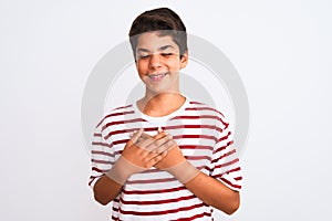 Handsome teenager boy standing over white isolated background smiling with hands on chest with closed eyes and grateful gesture on