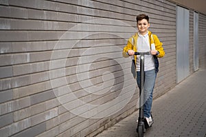 Handsome teenager rides on electric scooter down the city street.