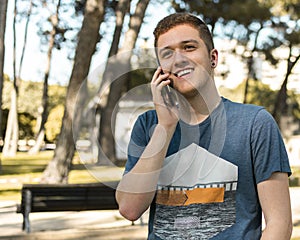 Handsome teenager talking on a mobile phone outdoors