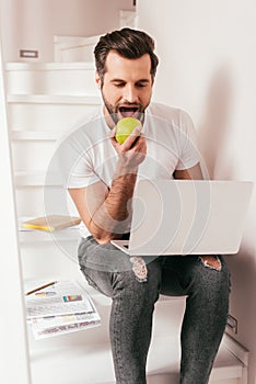 Handsome teleworker eating apple while working photo