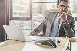 handsome thoughtful businessman sitting at workplace