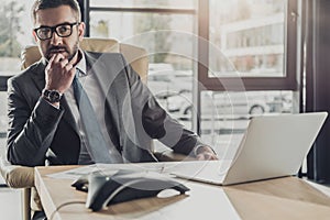 handsome thoughtful businessman sitting at workplace