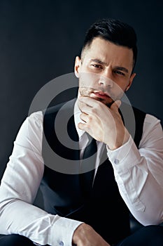 Handsome thoughtful man portrait in suit on dark background