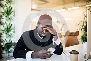 Handsome tired Afro American businessman in casual clothes while working with a laptop at home