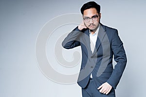 Handsome tired asian businessman wearing glasses in a jacket and trousers rubs his neck with his hand