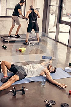 handsome tired sportsmen lying on yoga mat