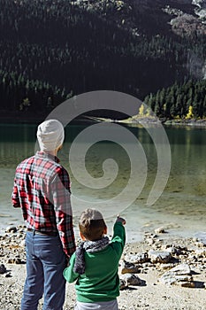 Handsome traveler with son looking at at the black lake, Montenegro