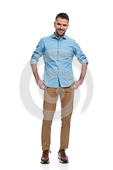 Handsome unshaved guy with chino pants and sneakers smiling