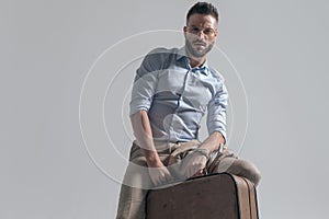 Handsome unshaved man with glasses holding suitcase and posing