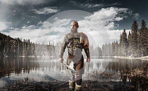 Handsome viking with axes standing at the lake