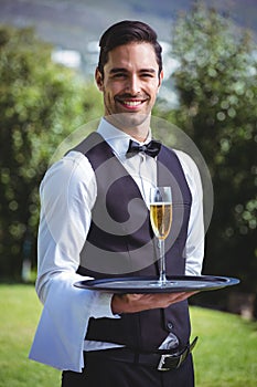 Handsome waiter holding a tray with glass of champagne