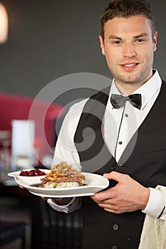 Handsome waiter serving appetizing duck dish